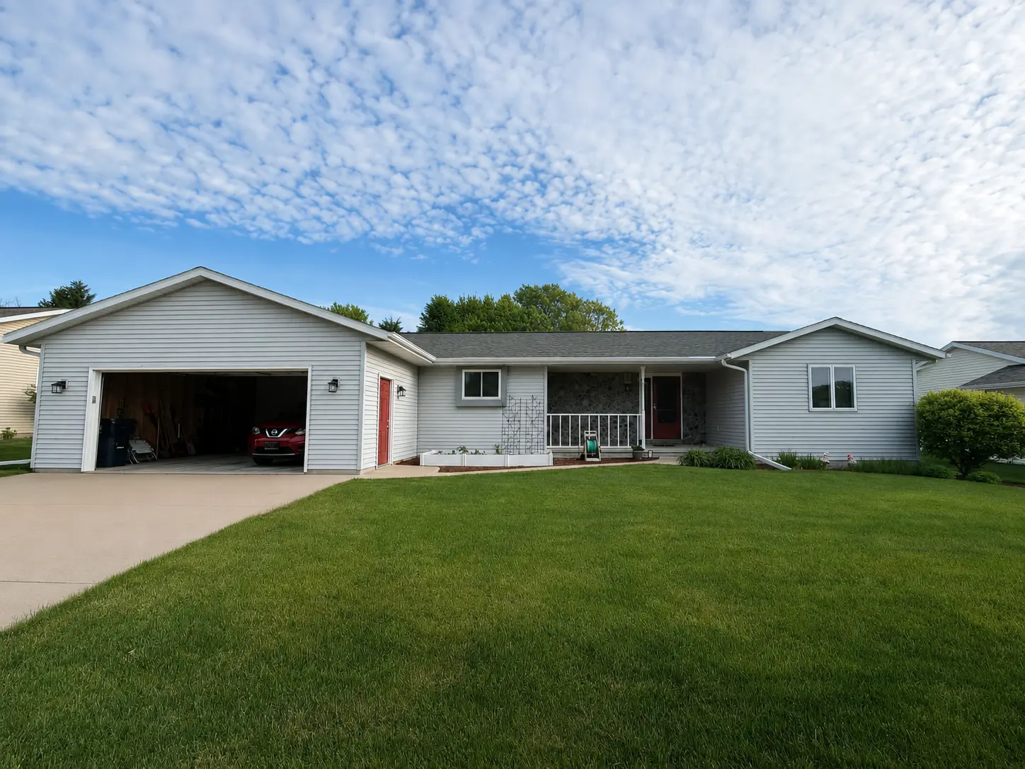 Grey sided ranch home with an attached garage and a newly replaced shingle roof under a mackerel sky.